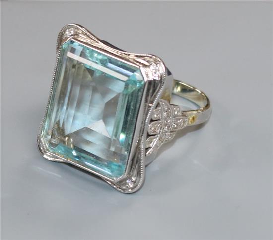 A large modern 9ct white gold and emerald cut aquamarine dress ring with diamond set shoulders, size W/X.